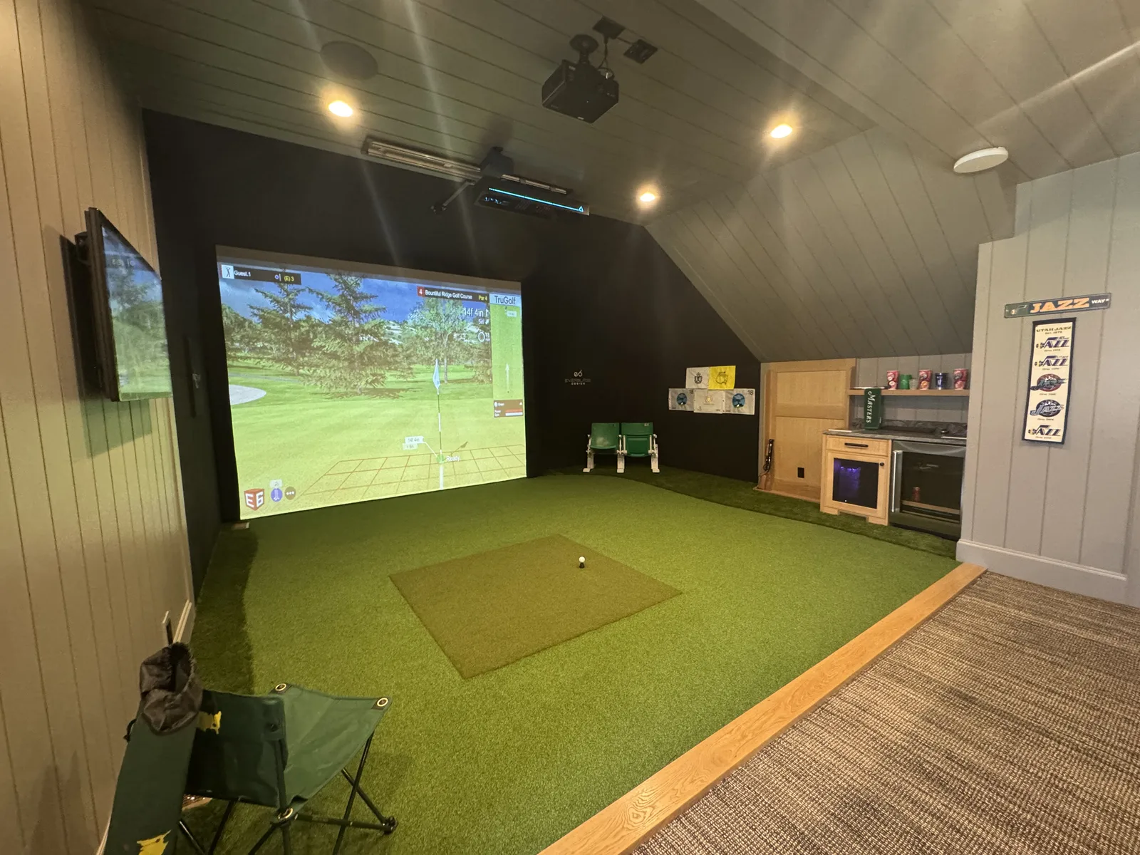 Home golf simulator room with EverBlade turf floor and hitting mat, TruGolf course on the impact screen